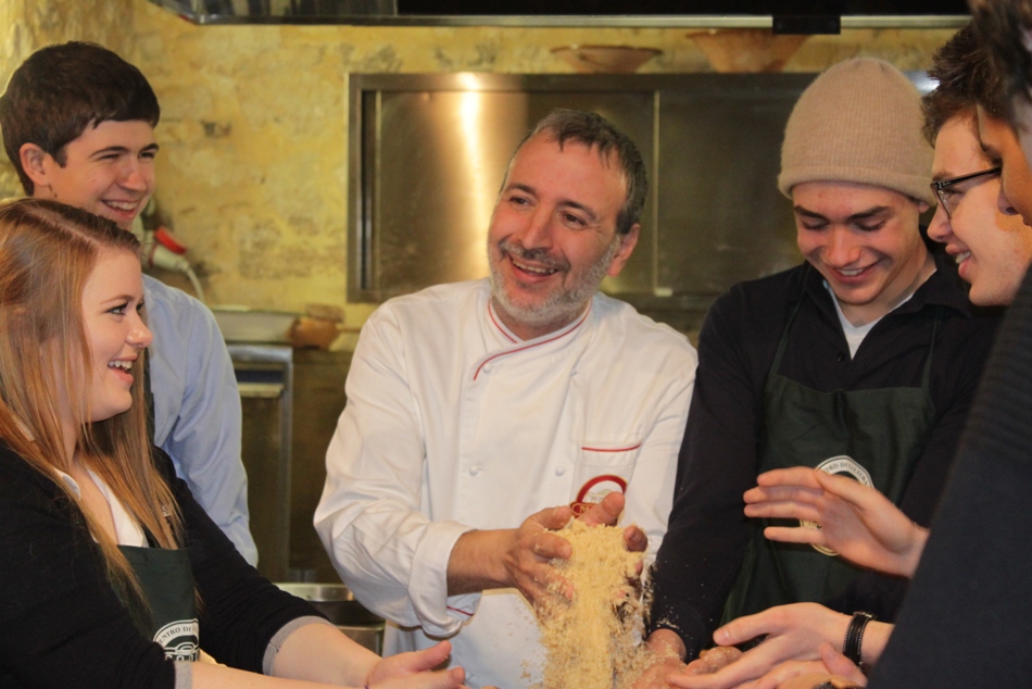 Ragazzi con uno chef mentre partecipano a un corso di cucina a Trapani